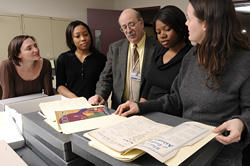 A group examining archival materials.